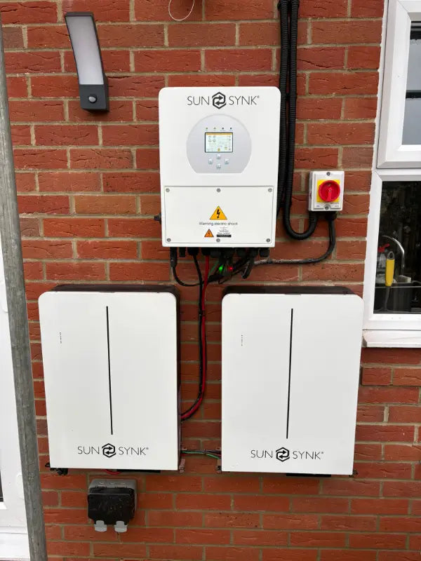 SunSynk inverter with two batteries on a brick wall
